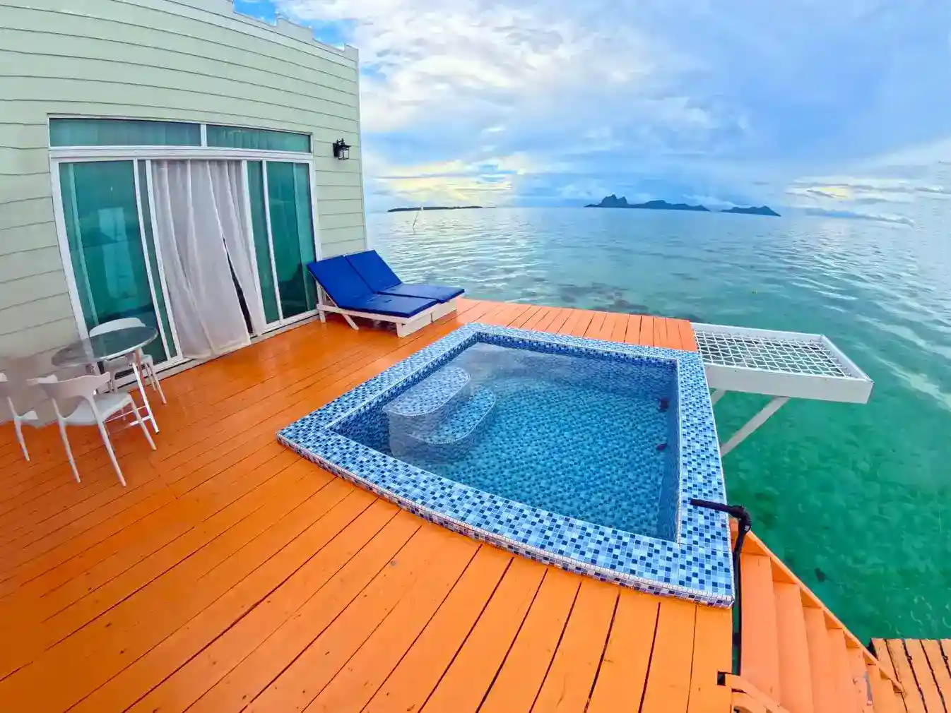 Enjoy your own plunge pool with a stunning view. Private overwater balcony at Danglai Resort featuring a personal plunge pool, lounge chairs, and a stunning view of Bohey Dulang.