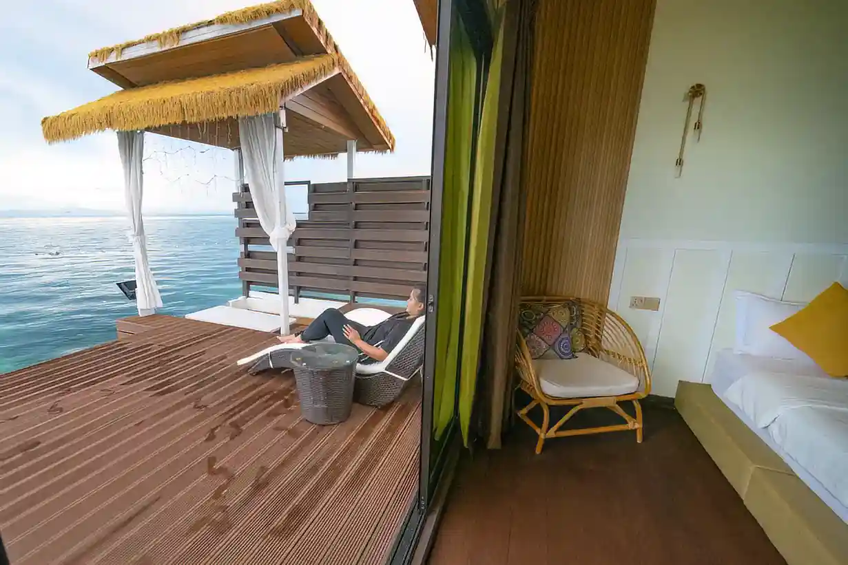 Enjoy serene sea views from your private balcony. Guest relaxing on a private, covered balcony at Dayang Resort, enjoying the serene sea views directly from their overwater chalet.
