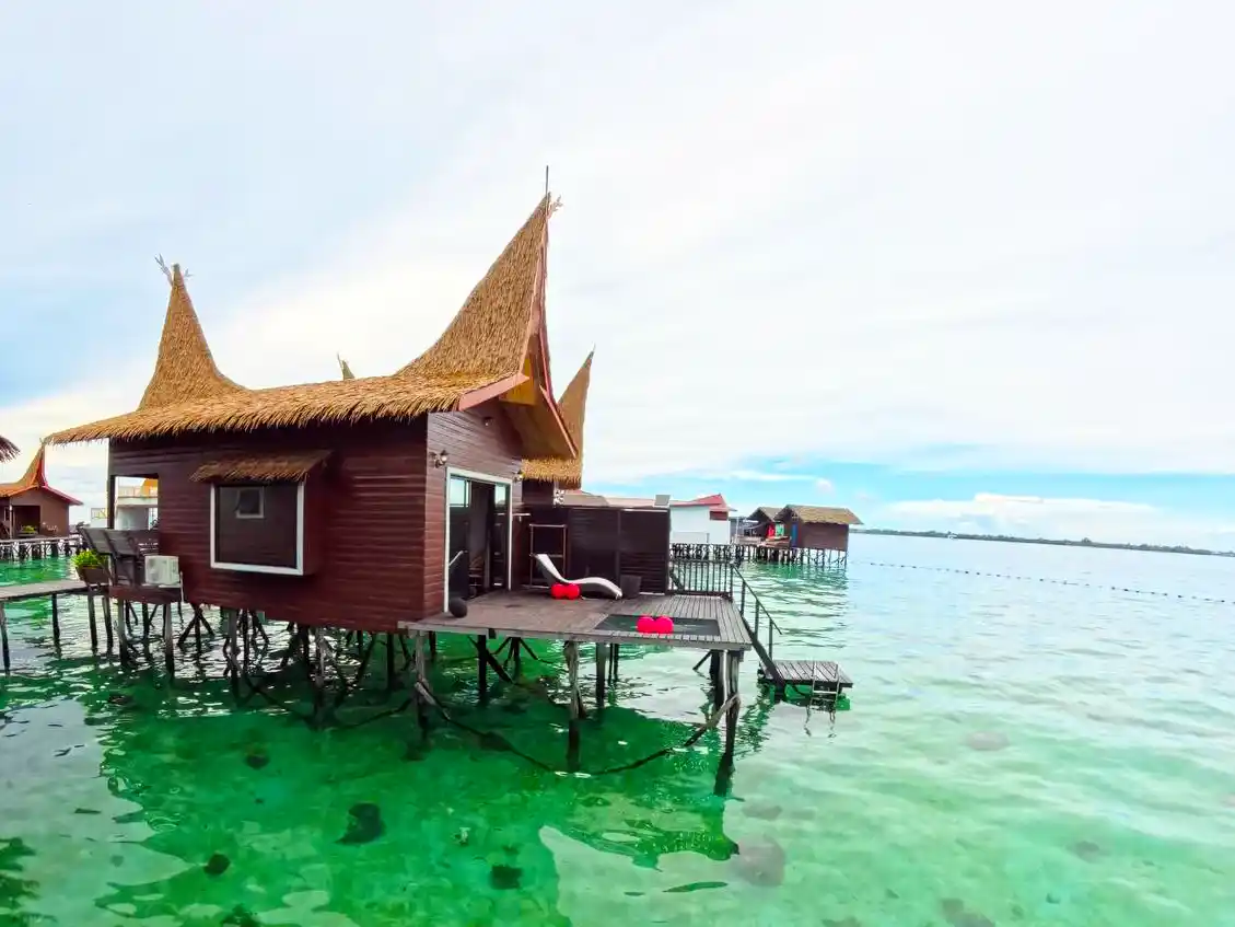 Step directly from your chalet into the sea. Private overwater chalet at Dayang Resort, featuring traditional thatched-roof architecture and a sundeck with direct stair access into the turquoise sea.